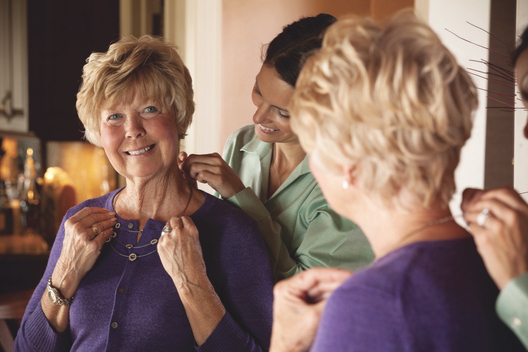 Homecare caregiver helping client with necklace