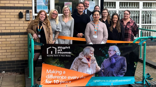 Right at Home Cardiff team stand with banner celebrating 10 year anniversary