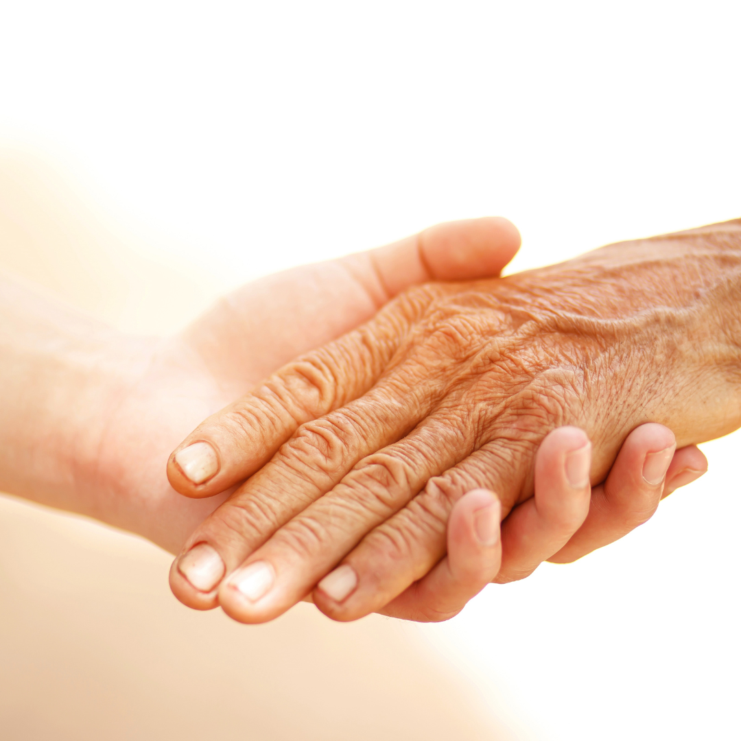 An older hand being gently held by a younger hand, symbolizing support for someone with dementia.