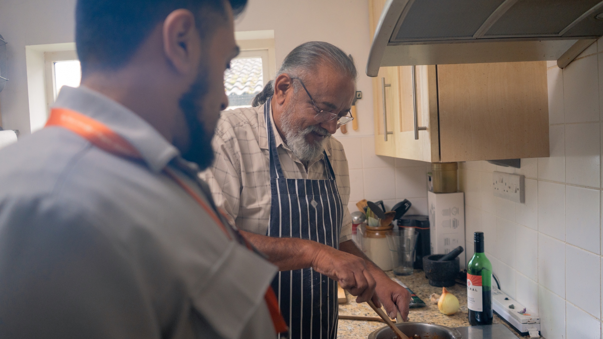 older man and caregiver cooking in kitchen