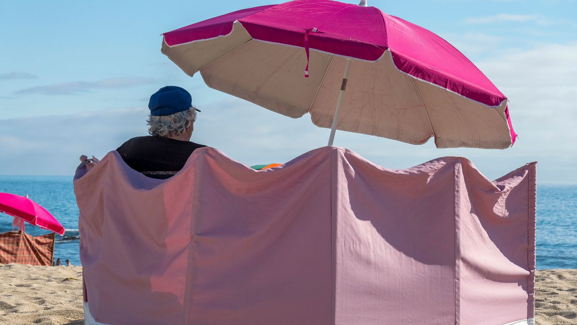 older person relaxing at the beach under parasol