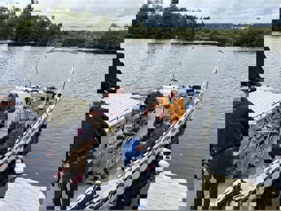 People wave from boat wrapped up in warm clothing