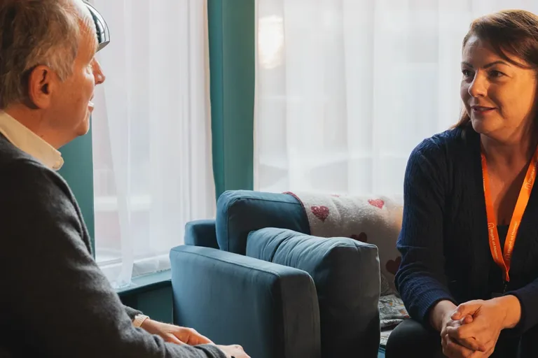 Carer talking with and supporting a person living with dementia at home