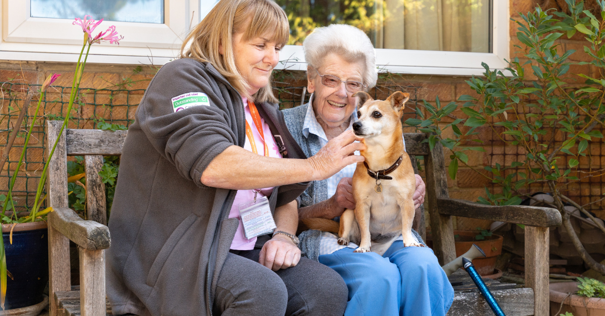 client smiles with her dog alongside a caring Right at Home Solent carer.
