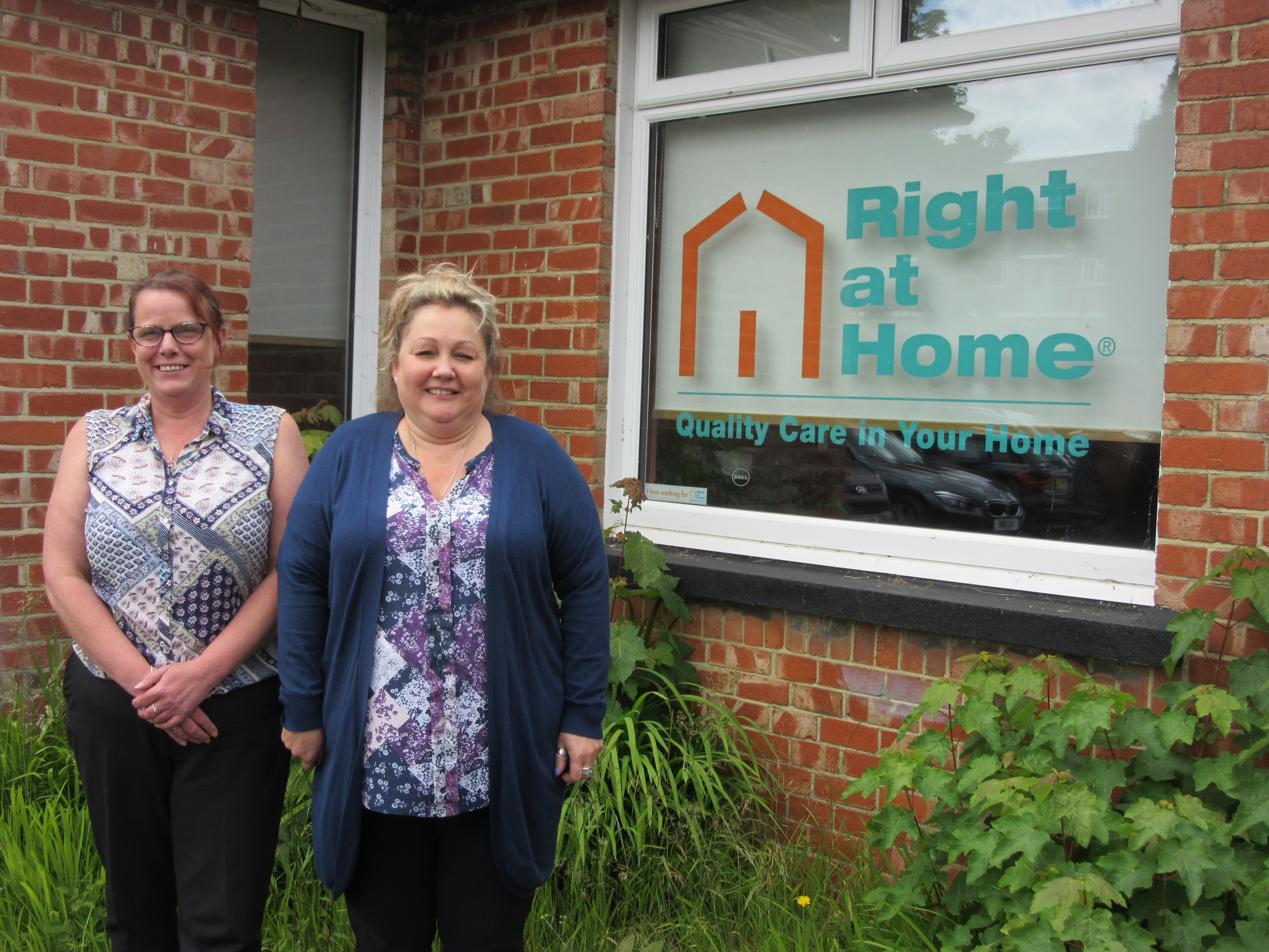 Two females standing in front of a window.