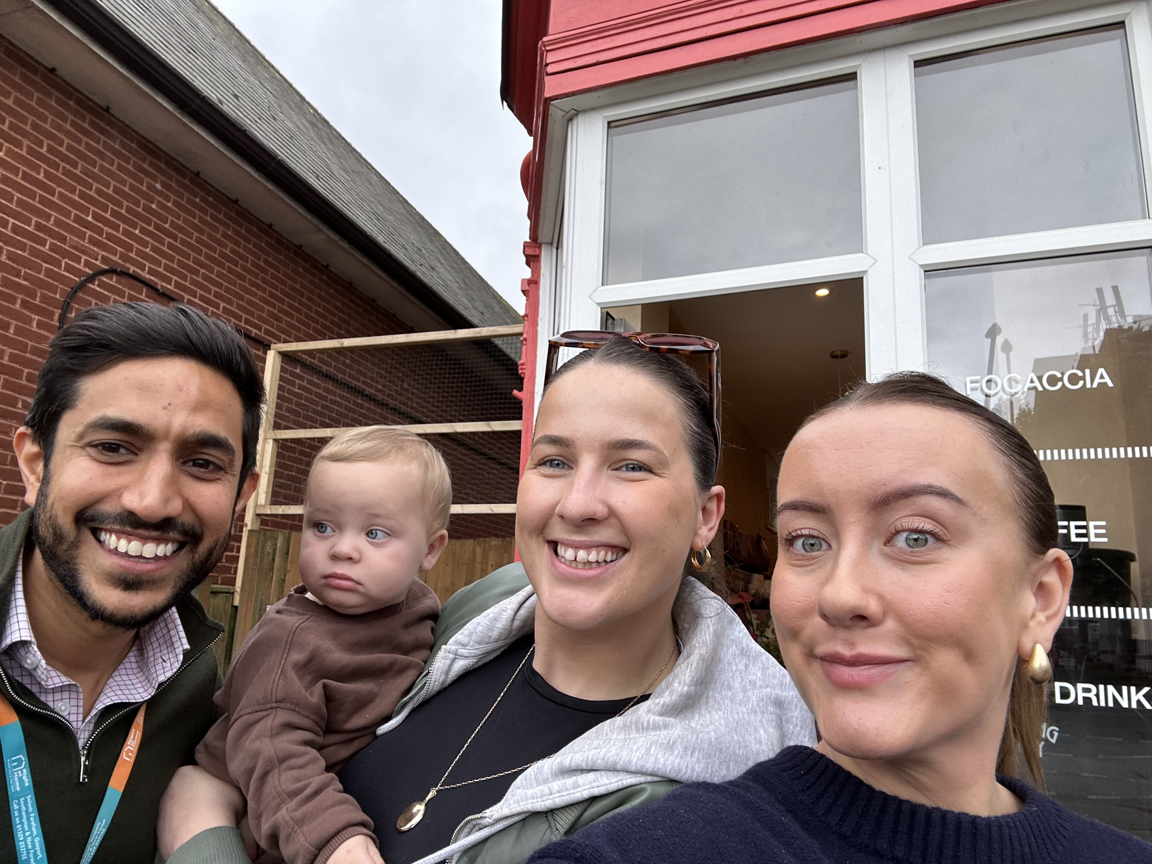 Director Kev Popat smiling with two women and a baby while taking a selfie, capturing a happy moment