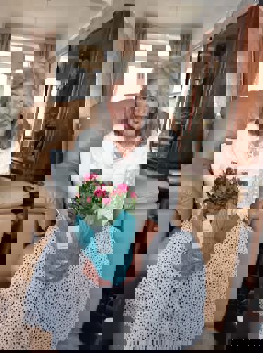 One of Right at Home Portsmouth's female clients holding a pot of flowers gifted to her by a Carer