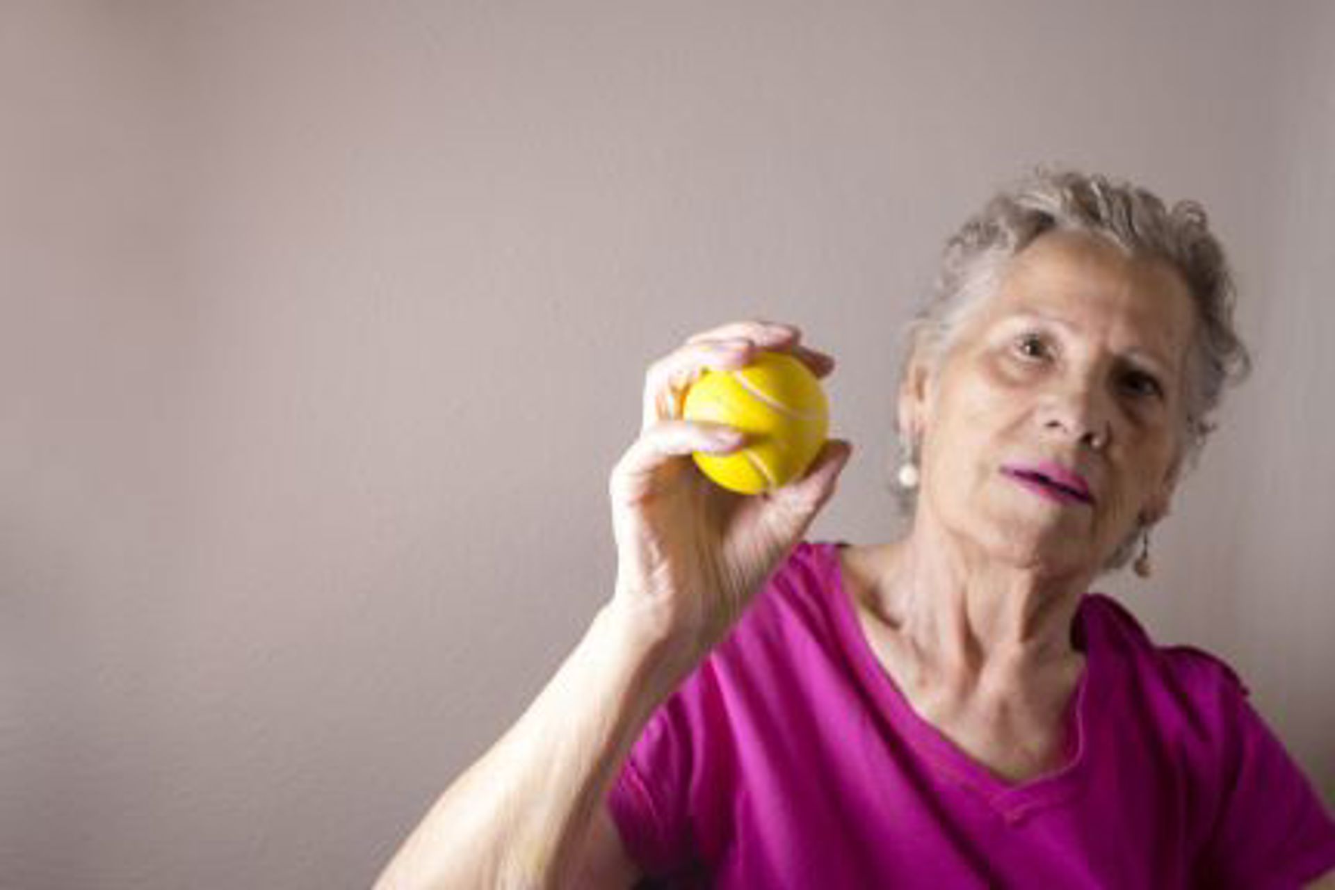 grey-haired-lady-squeezing-a-yellow-ball-as-part-of-her-stroke-rehabilitation-care-at-home-in-cheshire-squeezing-a-ball