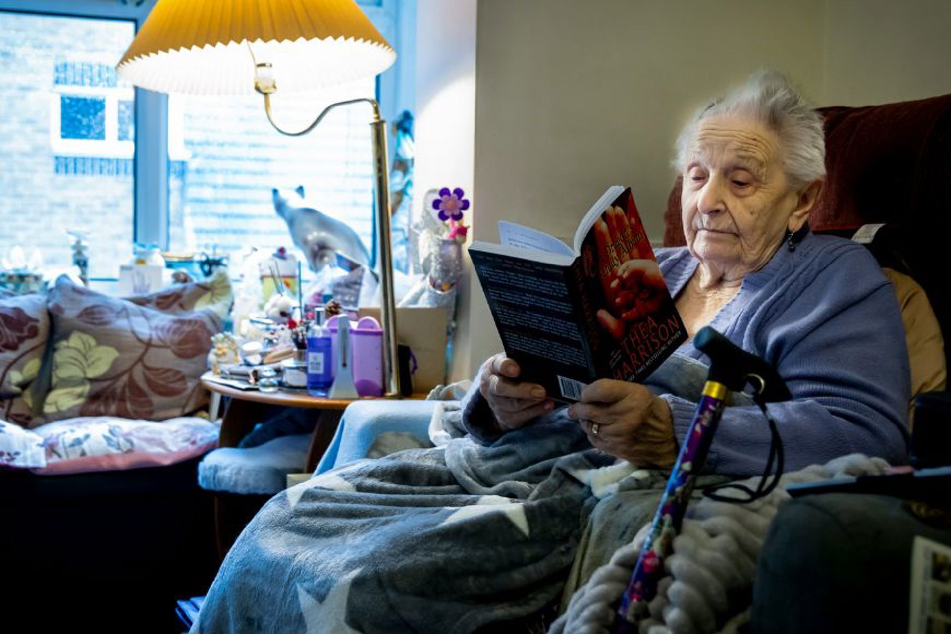 elderly-lady-sat-at-home-enjoying-reading-a-book-in-her-own-armchair-in-stockport